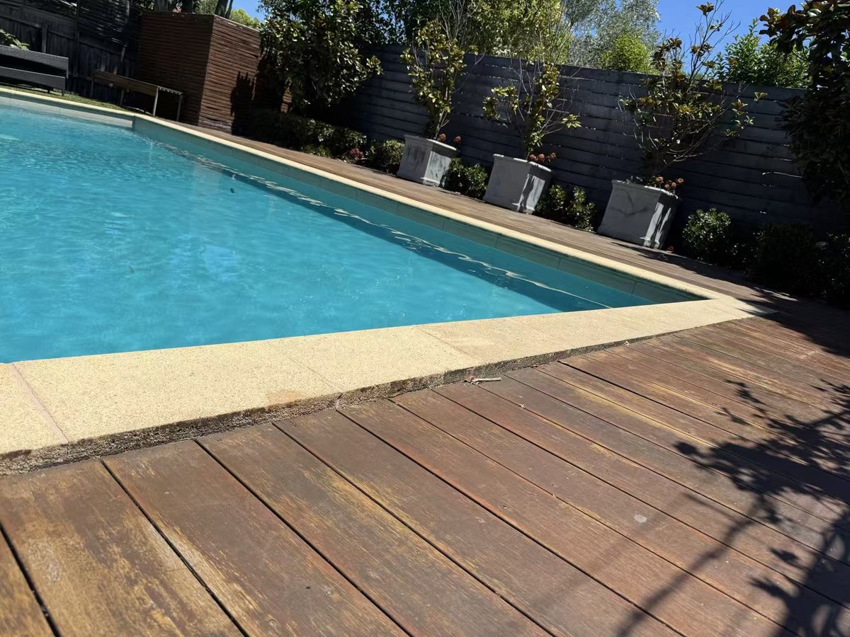 Worn deck sitting below the pool coping before works began