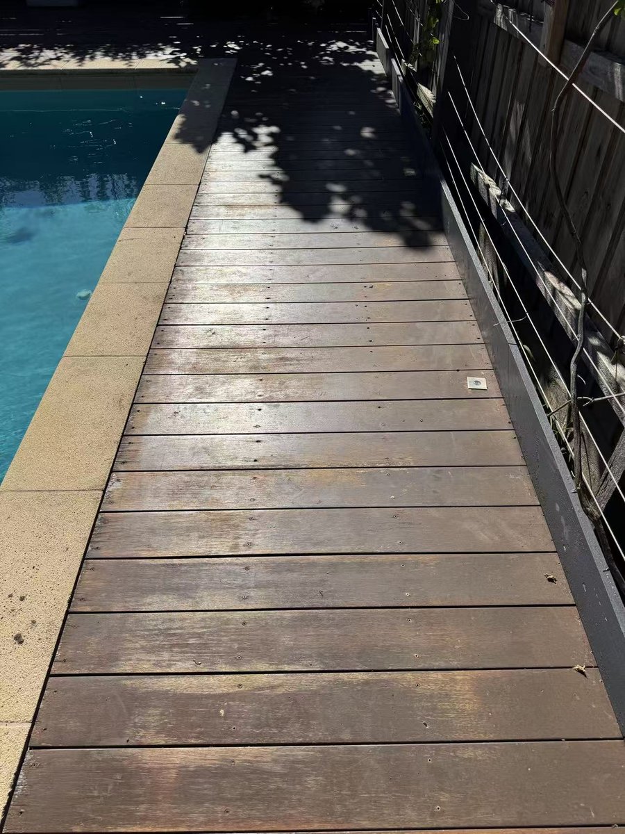 Deck walkway sitting low against the pool coping, with weathered boards