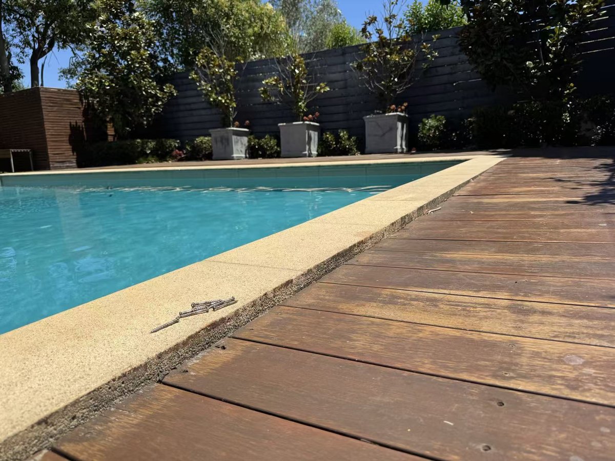 Deck sunk below the pool coping, boards unfastened ahead of the repair