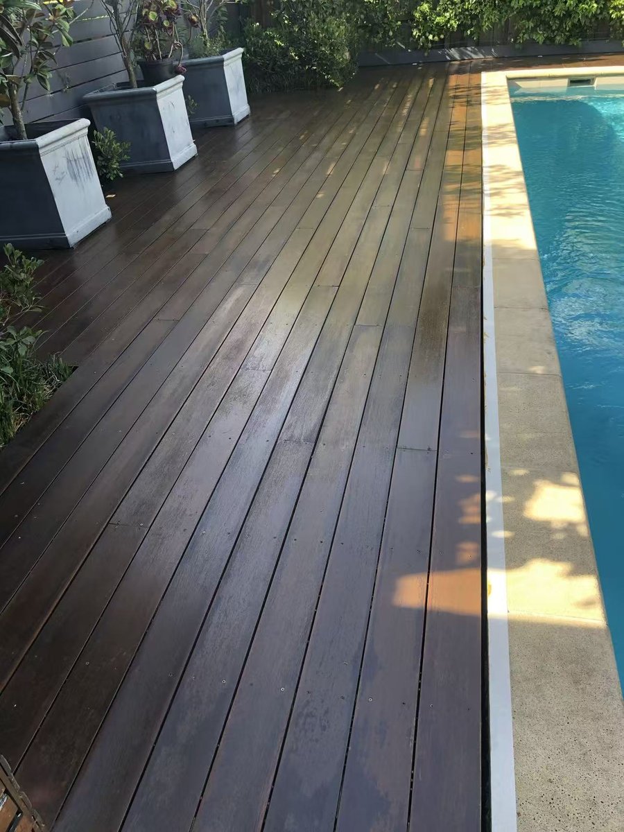 Re-stained deck sitting flush with the pool coping, with a rich, even finish
