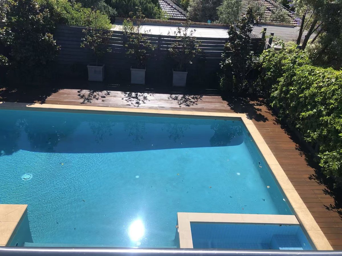 Finished deck sitting flush with the coping around the pool after restoration