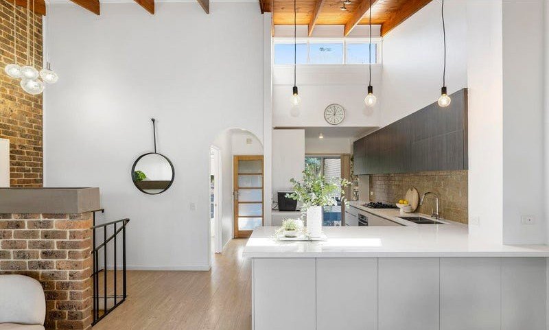 Kitchen with a white island bench opening onto the living area