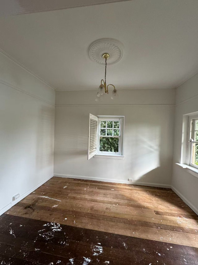 Interior room during repaint with paint splatter on timber flooring and chandelier