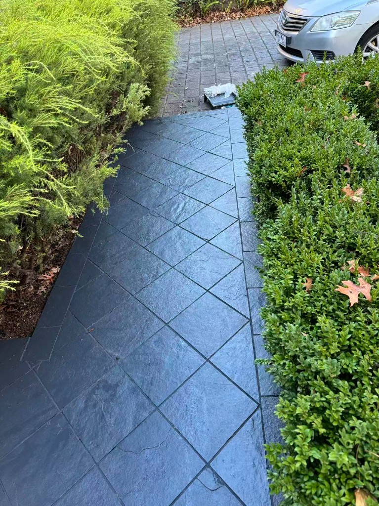 Finished outdoor walkway with diamond-pattern paving and landscaped hedges