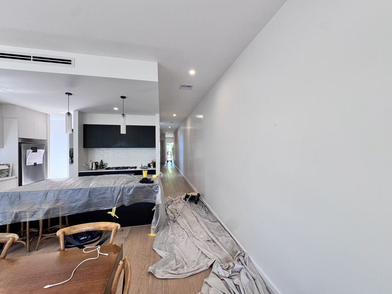 Caulfield pre-auction paint touch-ups — open-plan kitchen and dining with the long hallway feature wall prepped and protected