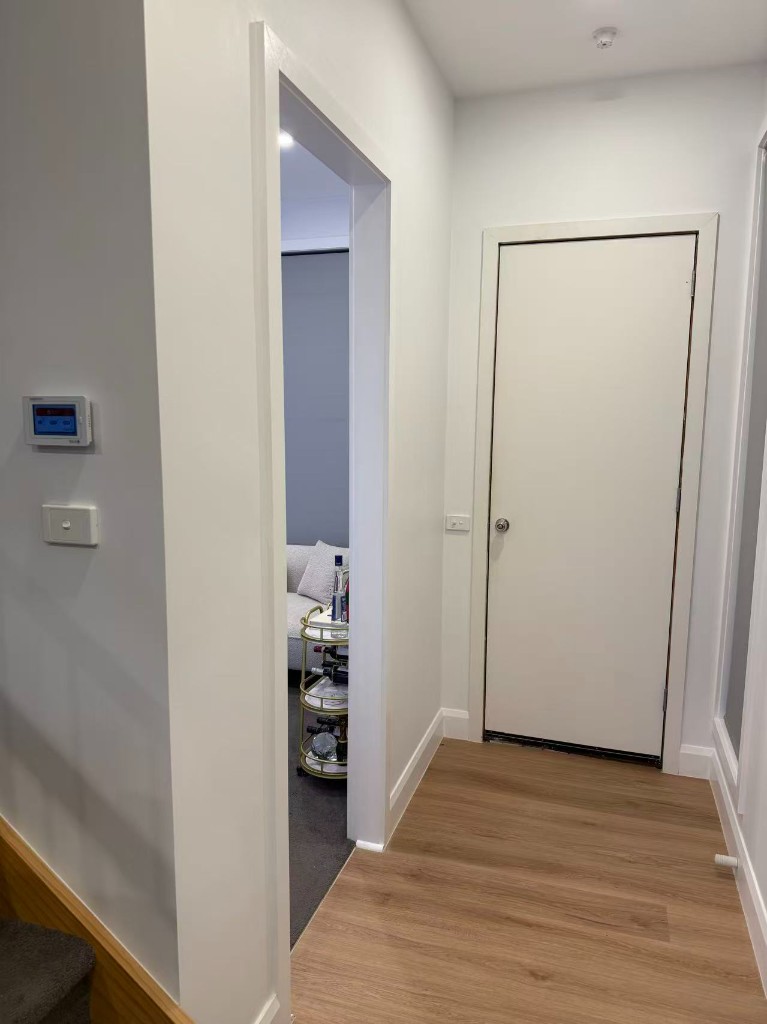 Chadstone full internal repaint — white hallway with wood-look flooring, doorway to grey-accent room
