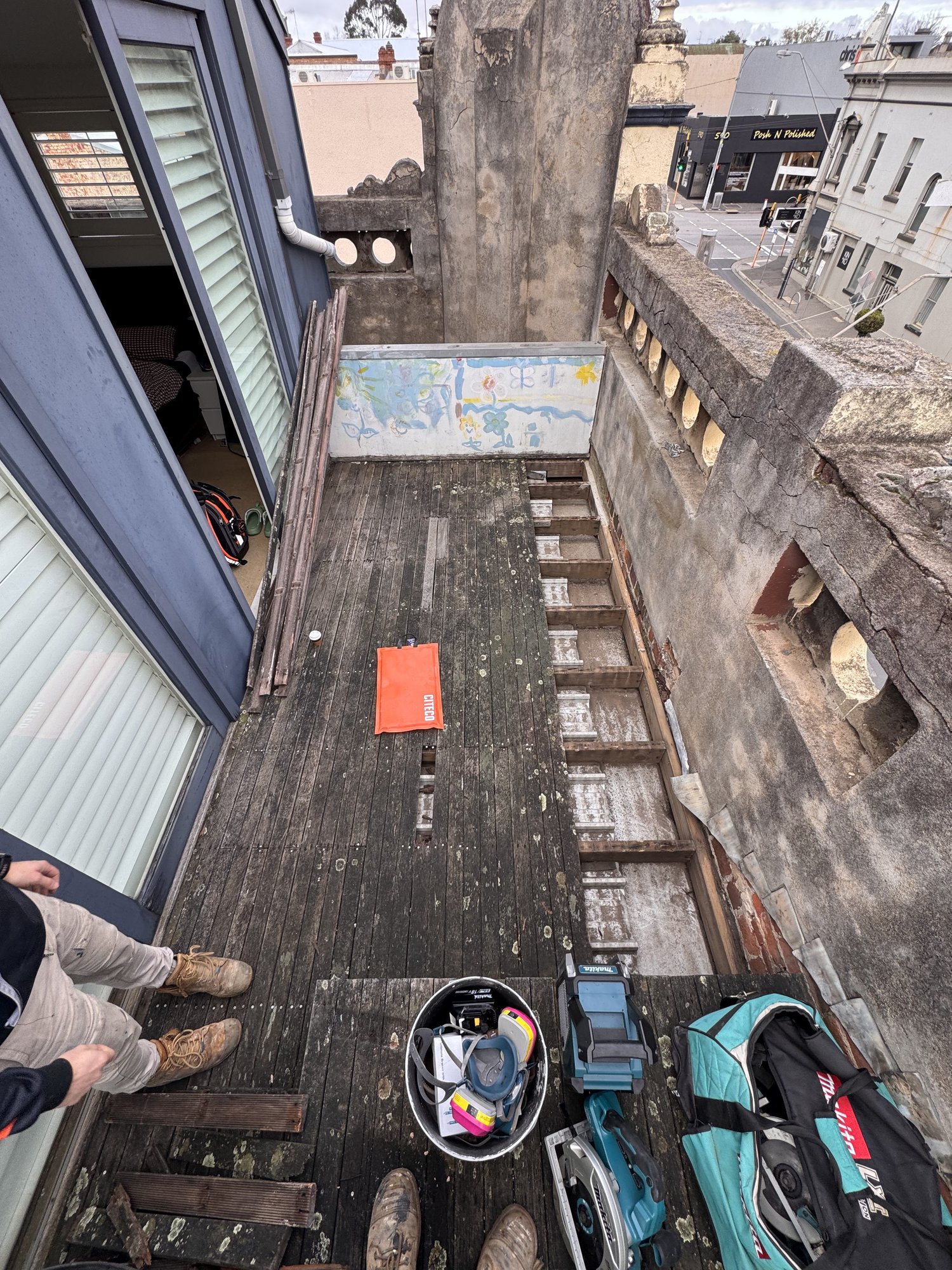 Aged merbau boards removed, timber joists exposed across the rooftop terrace