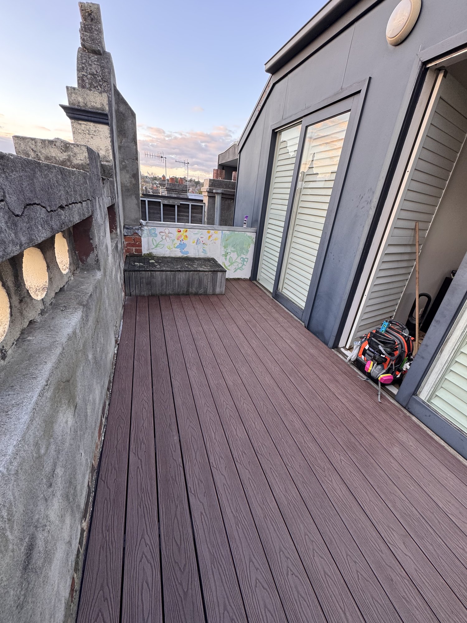 Finished reddish-brown composite rooftop deck under a clear sky