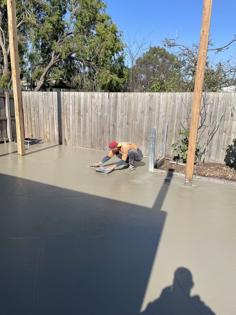 Hand-trowelling the freshly poured slab to a smooth finish around the drain