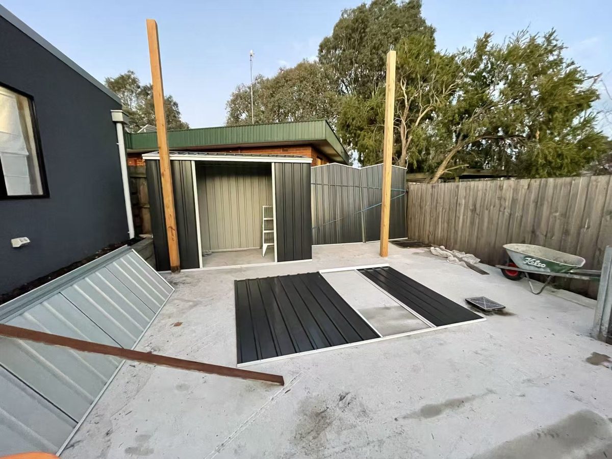 New Colorbond garden shed erected with roofing sheets laid out on the slab