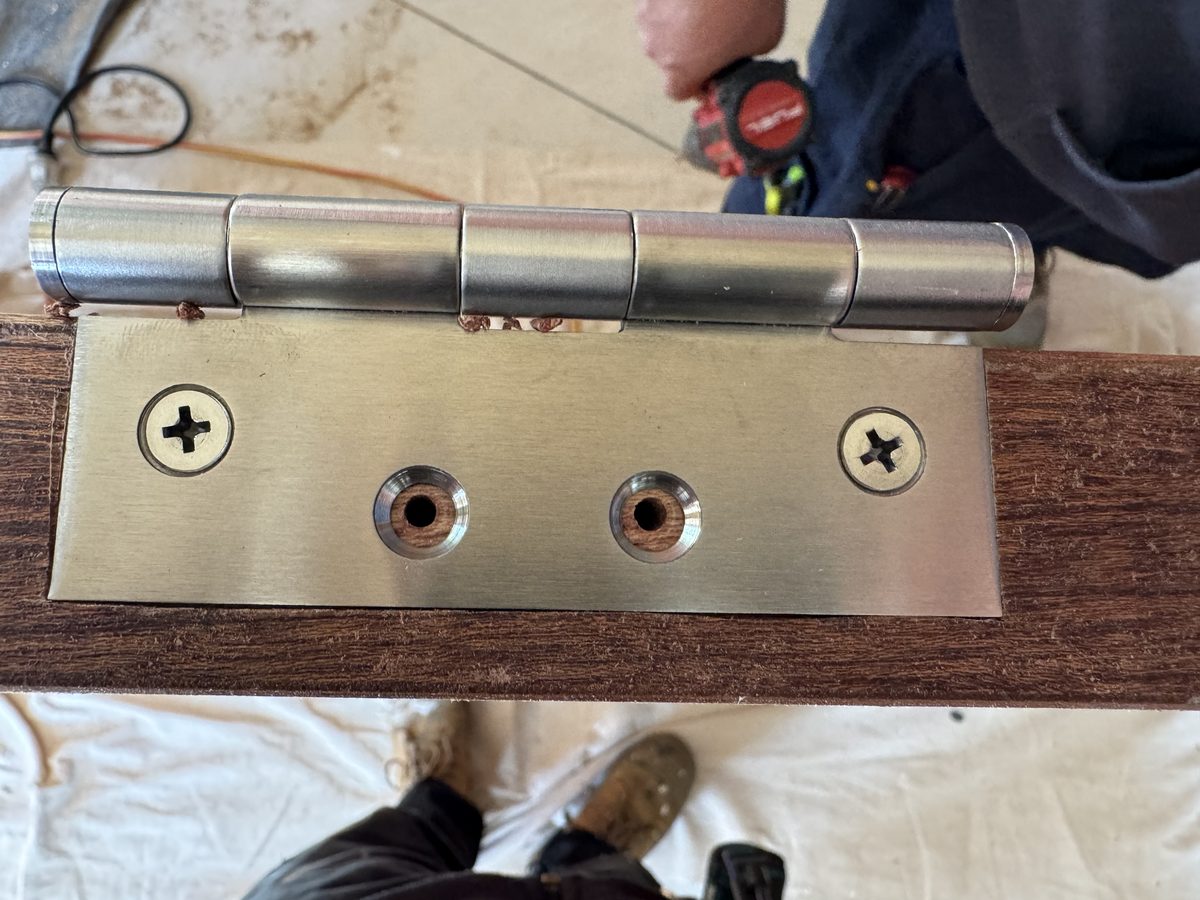 Close-up of hinge hardware being fixed with a drill